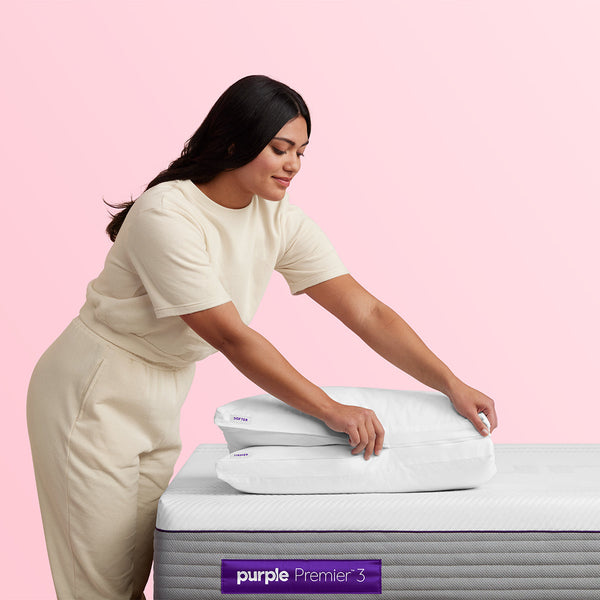 Woman Setting Pillows On The Purple Hybrid Premier 3 Mattress