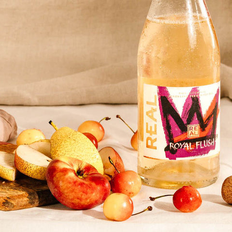 Bottle of Royal Flush Sparkling Tea next to a selection of stone fruits.