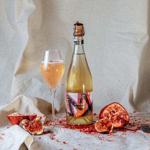 REAL Royal Flush Sparkling Tea Bottle and Champagne Flute with Pomegranate squeezed around.
