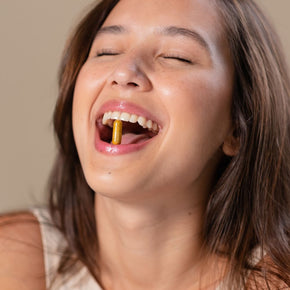 Junge Frau mit Vitaminkapsel im Mund