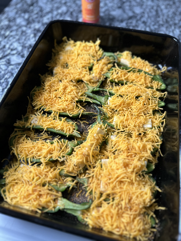 Halved jalapeno peppers stuffed with cheese and ready to grill