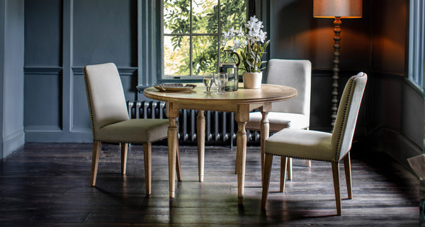 Round Dining tables with three upholstered chairs in a dark dining room