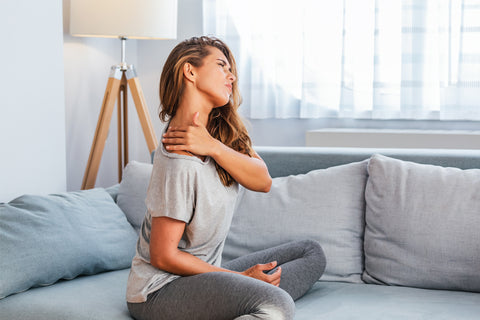 woman clutching on her shoulder due to muscle pain or discomfort