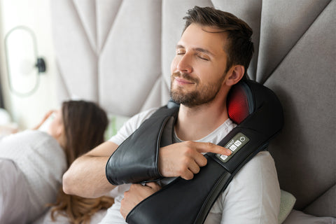 man lying in bed and enjoying vibration massage using neck massager