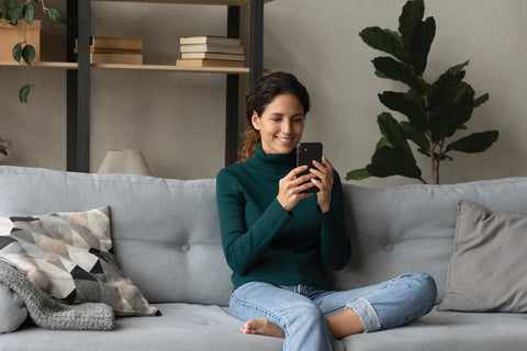 woman relaxing at home using her mobile phone to stay entertained