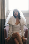 woman sitting on arm chair with white wedding dress and veil with light shining from behind