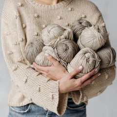 A woman holding a lot of yarn skeins