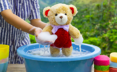 Washing a Stuffed animal in a bucket of water and soap