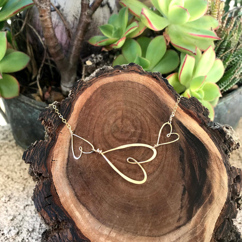 beth jewelry 3 small hearts necklace on wooden log display with succulents in backlground