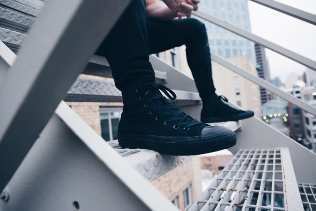 Close-up someone sitting on stairs wearing black pants and shoes