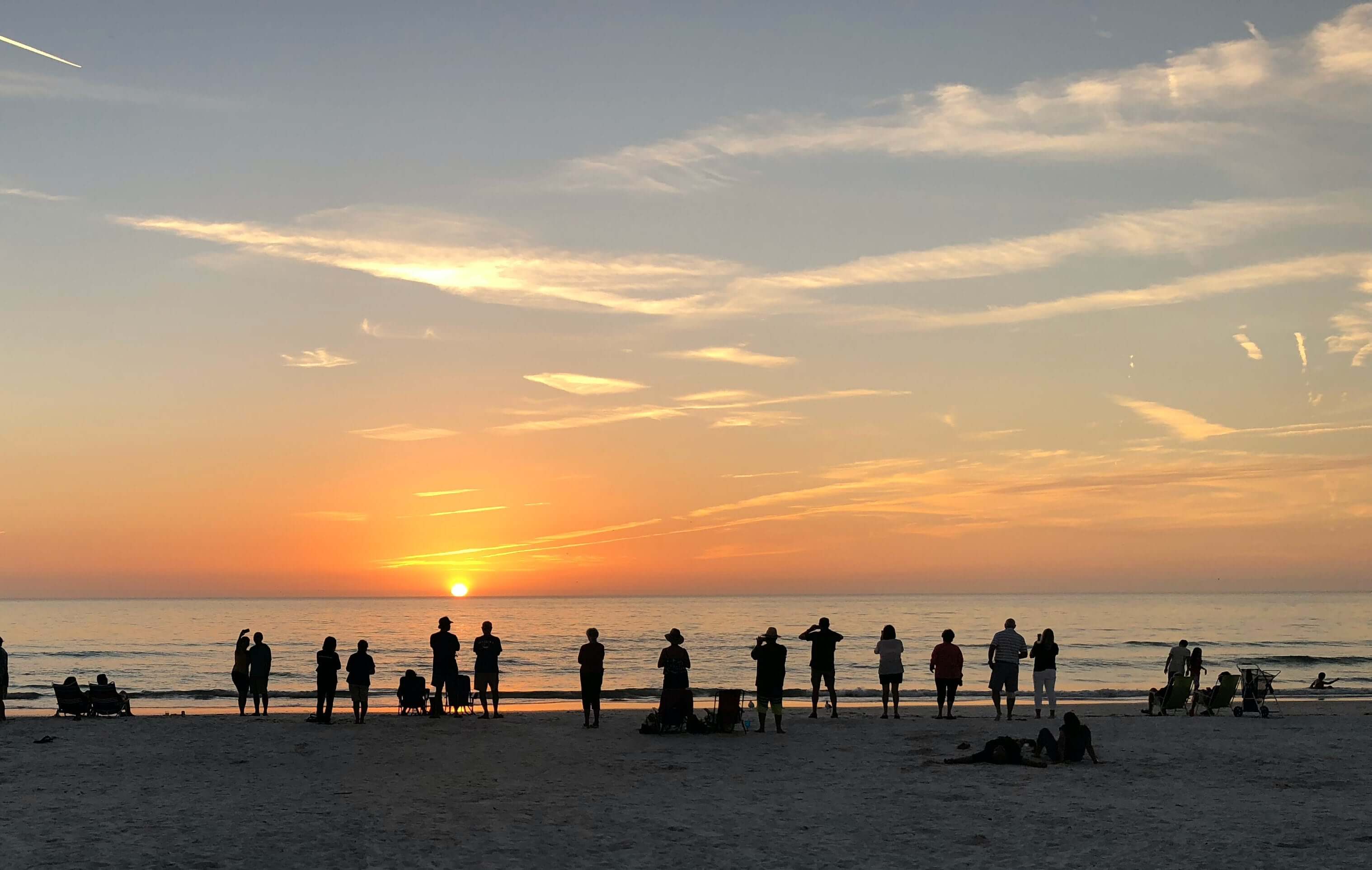 ビーチで夕日を楽しむ友人のグループ