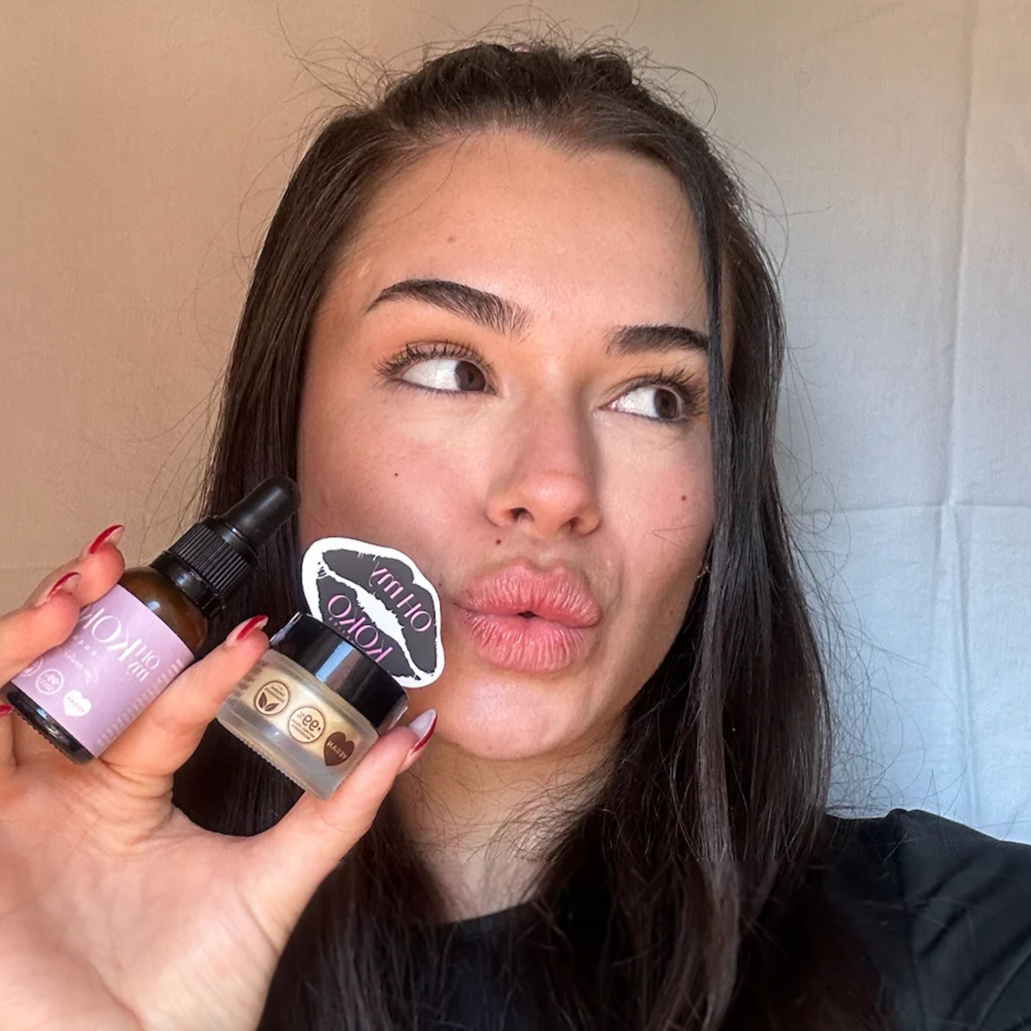 odelo sosteniendo el contorno de ojos y el labial de OhMyKoko, destacando el diseño minimalista, la sostenibilidad y la estética cuidada de la marca.