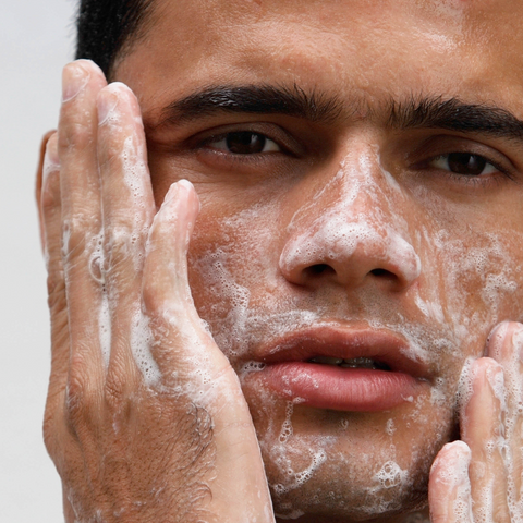 HANDSOME YOUNG MAN WASHING HIS FACE FOAM FACIAL CLEANSER