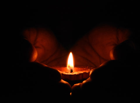 Image of two handles holding a small lit candle.