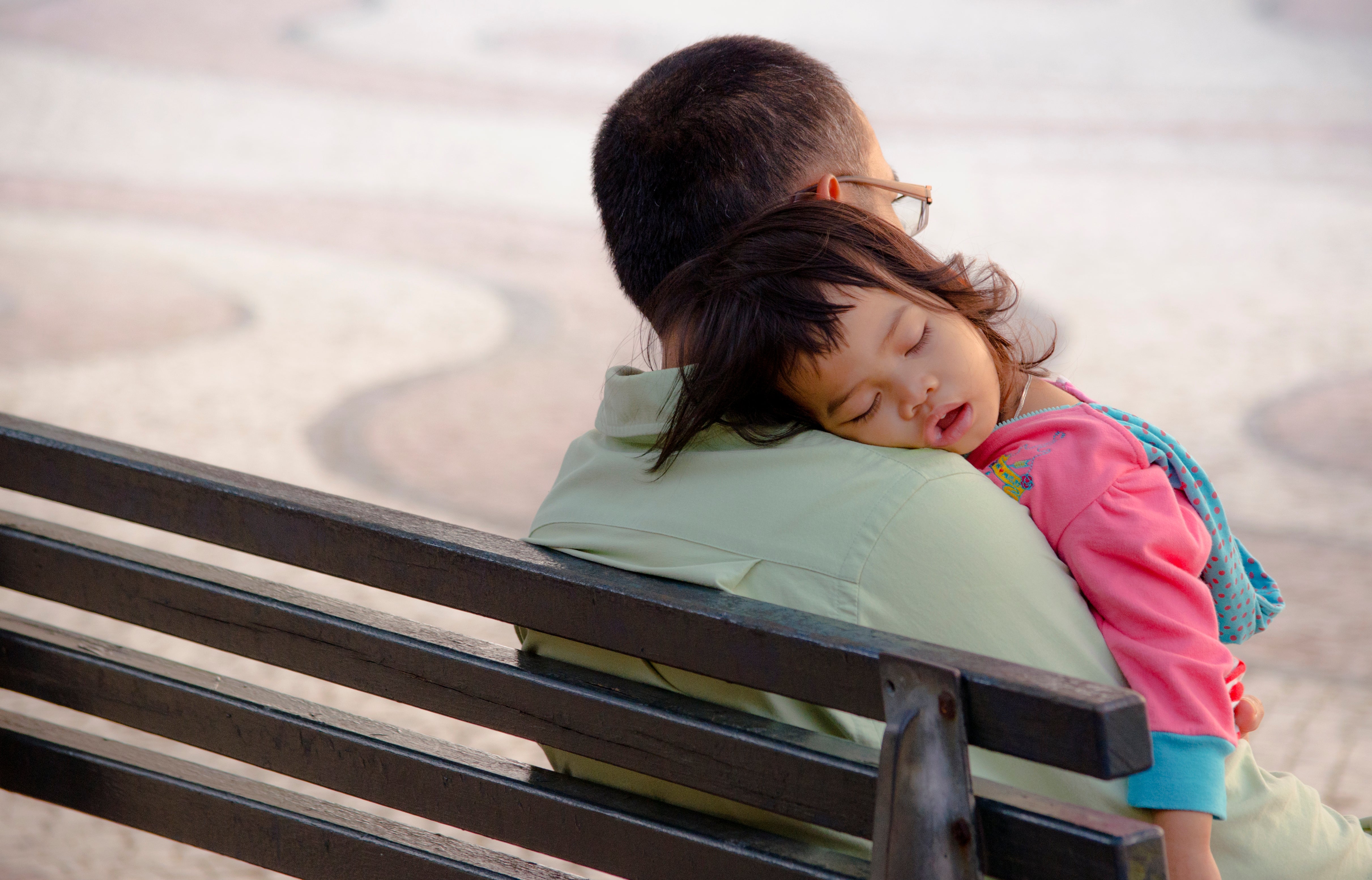 girl sleeping on father's shoulder