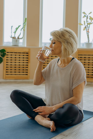 femme boit de l'eau tapis de yoga