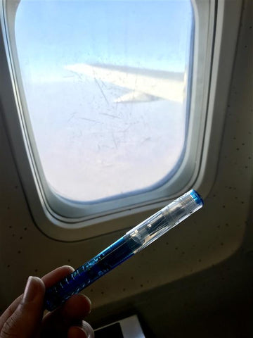A TWSBI pen held in front of an aeroplane window