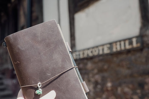 Traveler's Notebook held up in front of the sign for Stepcote Hill, Exeter