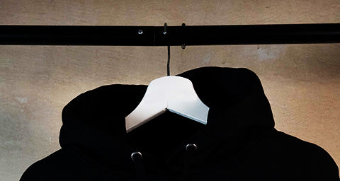 Schwerer Hoodie in schwarz auf schwarzer Kleiderstange