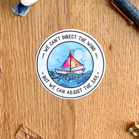 Vinyl Sticker which shows an illustration of a sailing boat at sea with the quote "we can't direct the wine but we can adjust the sails"