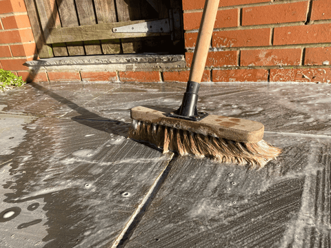 sandstone patio cleaning with brush, eco friendly soap and rainwater from a water butt