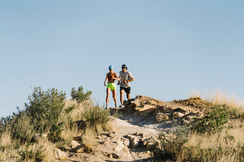 Two trail runners coming down a hill.