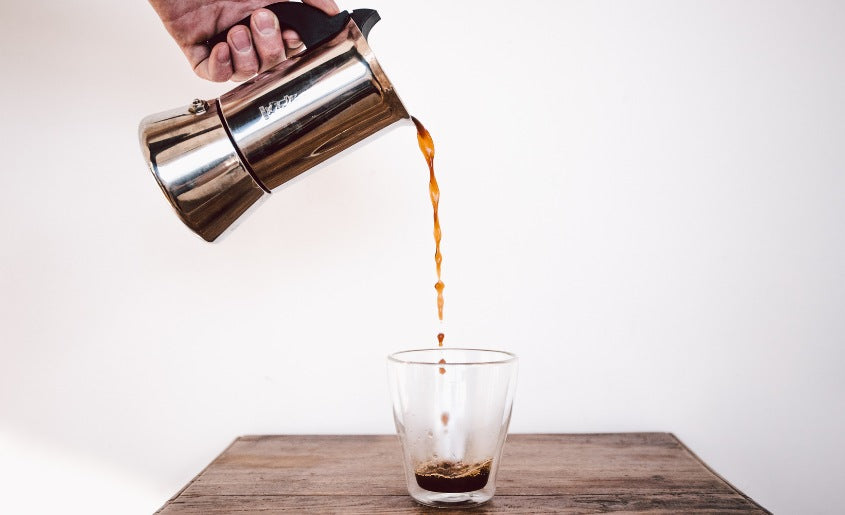 Pouring coffee into glass mixed with liquid mushroom