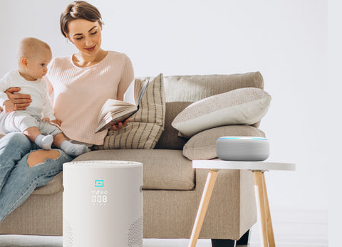 A woman holding her child on a couch in front of Eoleaf's AEROPRO 40 air purifier