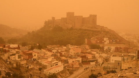 A castle under an orange sky polluted with Sahara desert dust