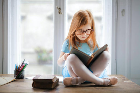 A child with glasses reading a book