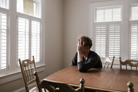 Depressed man with his hand on his head looking out a window
