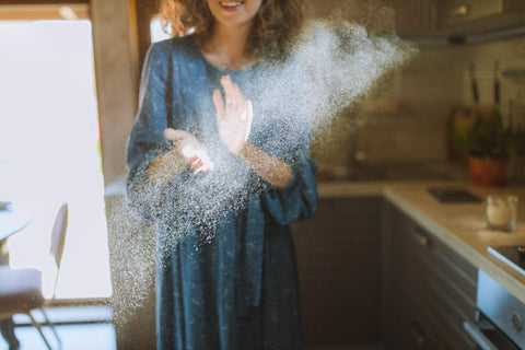Une femme debout dans sa cuisine avec la lumière du soleil montrant de la poussière dans l'air
