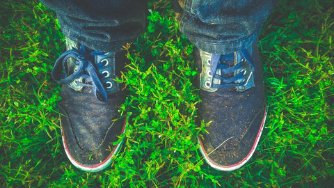 Une personne debout dans l'herbe avec des chaussures sales