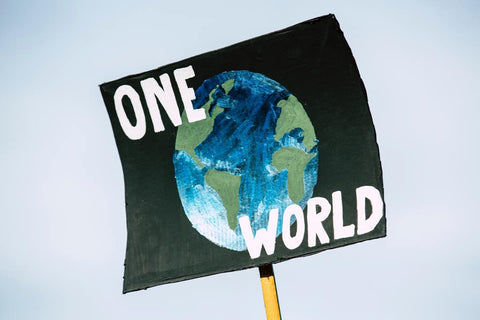 Un manifestant tenant une pancarte indiquant, 'Un seul monde'