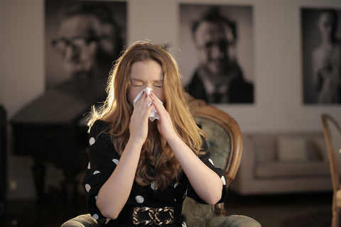 A woman blowing her nose into a tissue