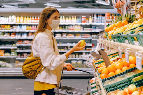 Une femme portant un masque faisant ses courses dans un supermarché