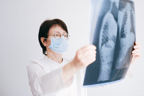 Un médecin masqué examinant une radiographie pulmonaire