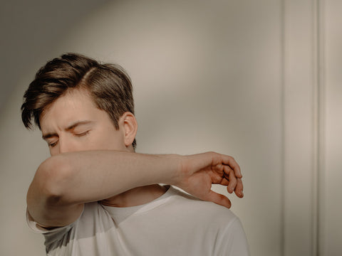 A man coughing into his arm