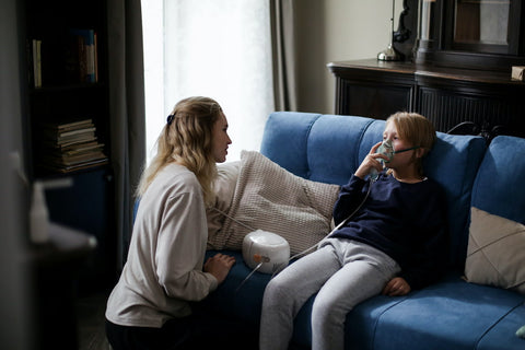 Une femme réconfortant son enfant qui utilise un inhalateur