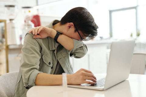 A man coughing into his arm