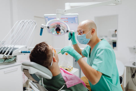 Un dentiste regardant à l'intérieur de la bouche d'un patient