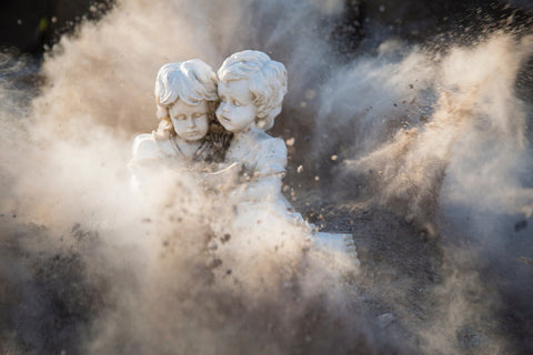 Two statues of children with dust exploding around them