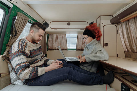 Deux personnes travaillant sur des ordinateurs portables dans un fourgon aménagé