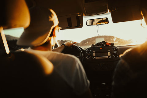 Un homme dans sa voiture roulant au coucher du soleil