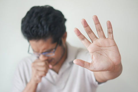 Un homme éternue avec la main tendue