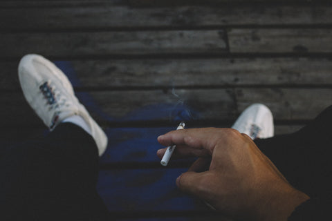 Un homme regardant sa main tenant une cigarette