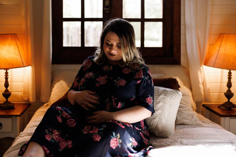 A pregnant woman laying on a bed looking at her stomach