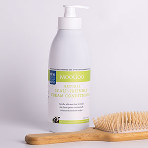 MooGoo Cream Conditioner with wooden hair brush laying next to it