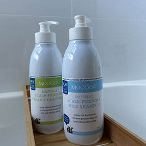 bottle of MooGoo Milk Shampoo and MooGoo Cream Conditioner in bamboo bath caddy