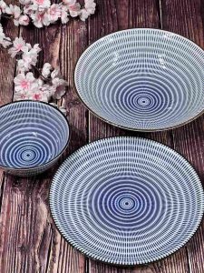 Blue and white Japanese tableware on a wooden table with pink flowers in the background.